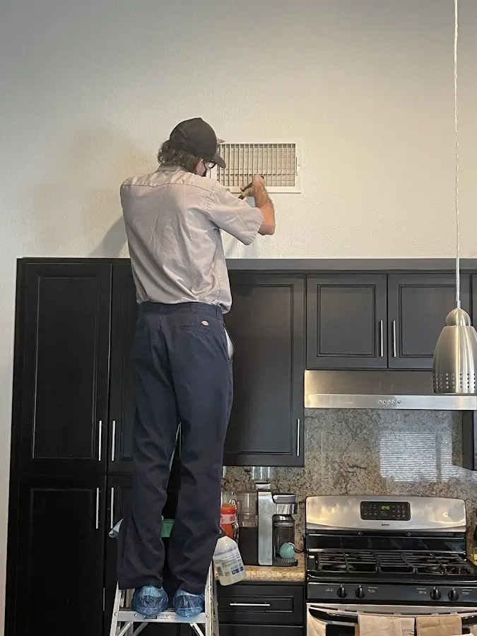 Technician inspecting an air vent during HVAC service in Runnemede